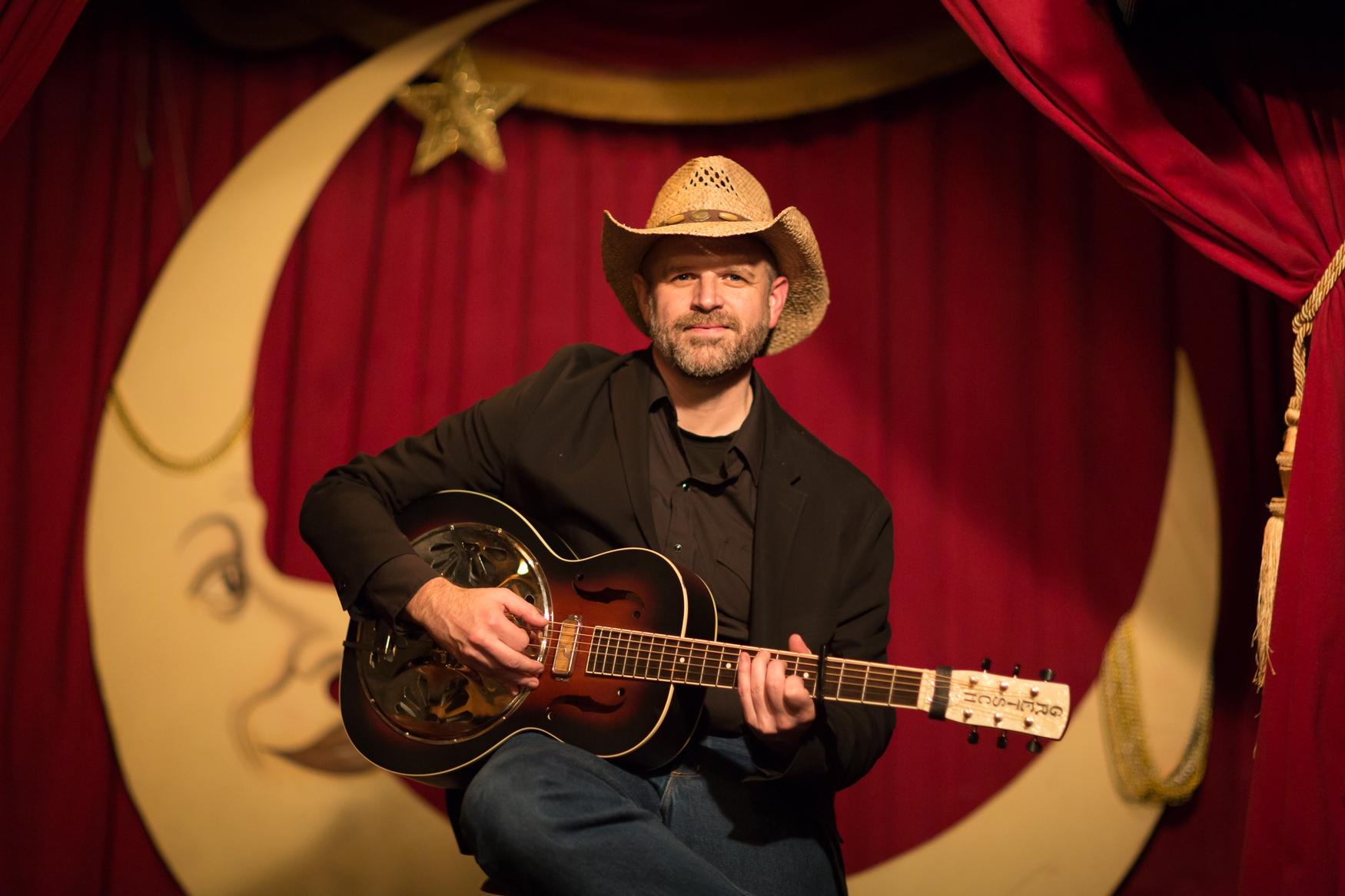 Man in cowboy hat with guitar on stage